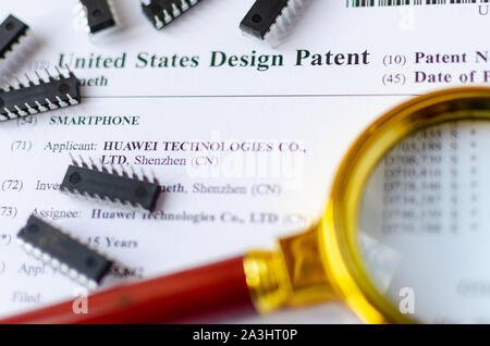 Die Nahaufnahme Foto von HUAWEI US-Patent, Lupe und Mikrochips. Chinesische Technologien sind Gegenstand der Untersuchung. Stockfoto