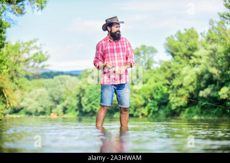 Ruhige und friedliche Stimmung. Fischer allein im Wasser des Flusses. Mann bärtigen Fischer. Fischer Angelausrüstung. Eine Art der Meditation. Fische in der Regel in freier Wildbahn gefangen. Trout Farm. Hobby Sport. Stockfoto