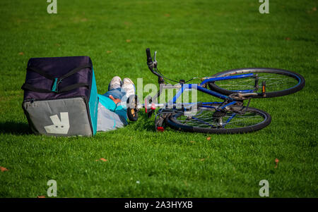 Deliveroo Food Delivery Courier ruht. Deliveroo Courier macht eine Pause zwischen den Lieferungen von Lebensmitteln. Stockfoto