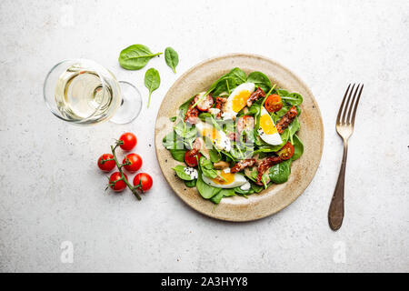 Salat mit Spinat, getrockneten Tomaten und Eier. Gesunde Hausmannskost. Konzept für eine leckere und gesunde Mahlzeit. Ansicht von oben. Kopieren Sie Platz. Stockfoto