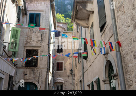 Montenegro - Flaggen der verschiedenen Staaten dekorieren eine schmale Straße in Kotor Stockfoto