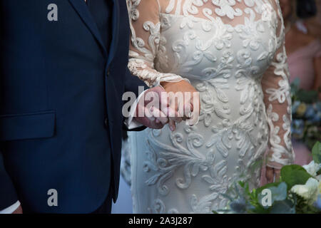 Nahaufnahme der Braut und des Bräutigams halten sich an den Händen und sagen ihr Gelübde und tauschen Ringe am Tag ihrer Hochzeit in Worcestershire, England Stockfoto