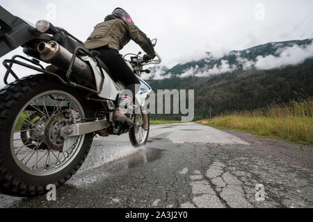 Eine Frau reitet ihr Motorrad an einem bewölkten Sommertag. Stockfoto