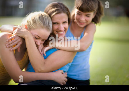 Porträt einer Mitte der erwachsenen Frau umarmt werden von ihren zwei Töchtern im Teenageralter. Stockfoto