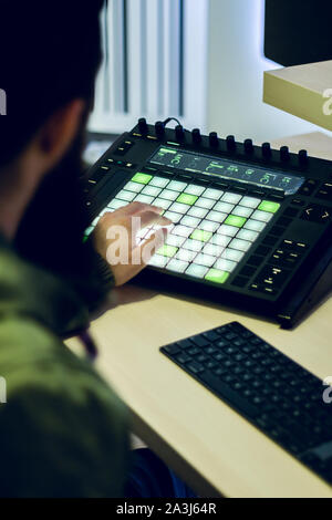 Bärtige junge Deejay produziert elektronische Musik in seinem Studio Stockfoto