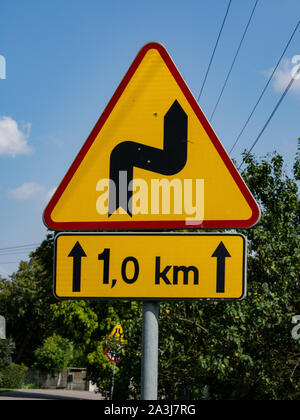 Gefährliche biegen Sie rechts ab, dann nach links. Verkehrszeichen auf einer Landstraße. Warnung Schild. Gefährliche Straße. Niebezpieczeństwo, wskazana ostrożność. Stockfoto