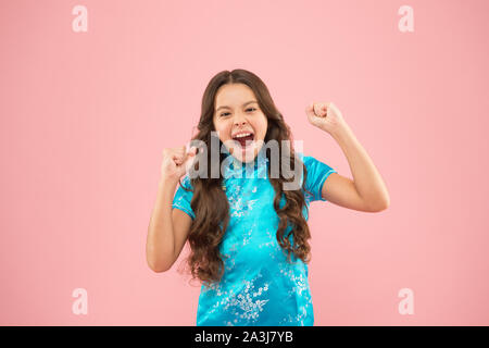 Shes ein echter Gewinner. Kleines Mädchen schreien und Sieger Geste auf rosa Hintergrund machen. Gerne kleine Sieger aktive Gestik im chinesischen Stil. Sieger feiern Sieg oder Erfolg begeistert. Stockfoto