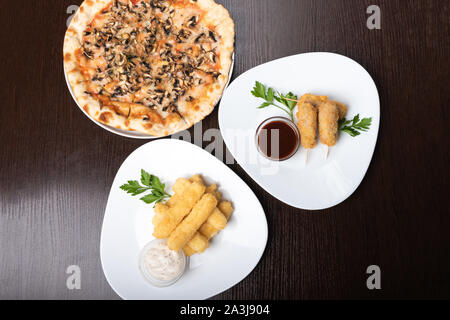 Korndog auf Spieße und käsestange. Pizza. Auf den Tellern. Stockfoto