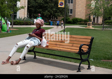 Muslimische Frau student mit Handy das Tragen eines hijab oder Oberteil sitzen auf einer Bank an der St. Thomas University. St. Paul Minnesota MN USA Stockfoto