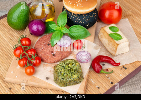 Vegane Burger, Brötchen, Tofu und Gemüse auf einem Holzbrett bereit zum Kochen Stockfoto