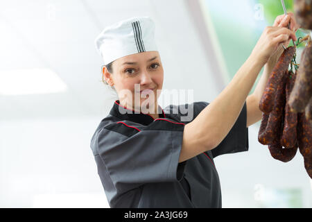 Frau Metzger holding Würstchen bei Fleisch Fabrik Stockfoto