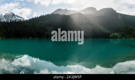 Die Sonne scheint durch Regen und Wolken über Joffre Lake. Stockfoto