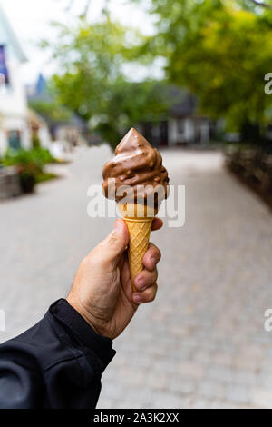 Mann mit Abblendlicht Schokolade Eis in der Hand, sehr unscharfen Hintergrund, kleine Tiefenschärfe. Der dunkle Hintergrund. Stockfoto