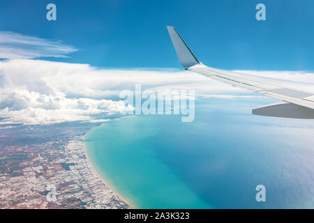 Blue Sky High wing Blick auf die Küste von einem Flugzeug, weit weg weiße Wolken Stockfoto