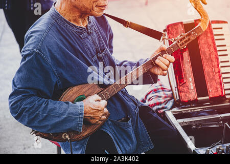 Thailändische folklore Musiker spielen Folk Song mit Stift (Isan Gitarre) traditionelle Musik Instrument zur Straße zeigen Stockfoto