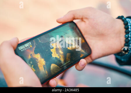 Bischkek, Kirgisistan - Oktober 10, 2019: Ladebildschirm mit Logo. Mann spielt online Spiel Call of Duty Mobile auf dem iphone 11. Stockfoto