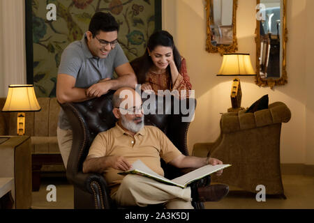 Vater, Mutter und Sohn sind auf der Suche nach einem Buch. (Familie) Stockfoto