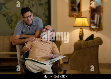 Vater und Sohn sind auf ein Buch und Lachen. (Familie) Stockfoto