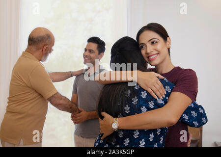 Mutter und Tochter sind umarmen einander, während Vater und Sohn im Gespräch in der Rückseite sind. (Familie) Stockfoto