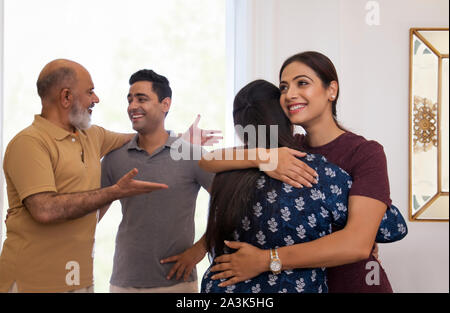 Mutter und Tochter sind umarmen einander, während Vater und Sohn im Gespräch in der Rückseite sind. (Familie) Stockfoto