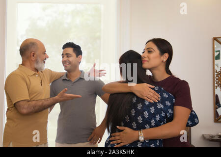 Mutter und Tochter sind umarmen einander, während Vater und Sohn im Gespräch in der Rückseite sind. (Familie) Stockfoto