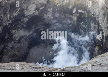 Detailansicht der Innenraum des Mount Bromo Krater, Ostjava, Indonesien. Weiß vulkanisches Gas steigt von unten. Gelber Schwefel im Rock zu sehen. Stockfoto