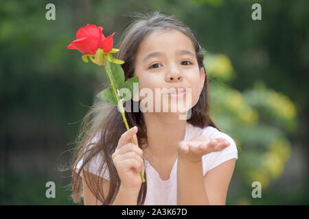Mädchen bläst Küsse mit einer Rose Stockfoto