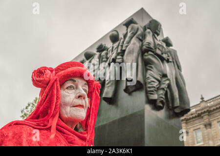 Whitehall, London, UK. - Oktober 7, 2019-XR ptotests - "Rote Brigade' Art Gruppe, während einer Straße Leistung, "Frau des Zweiten Weltkriegs" im Hintergrund Stockfoto