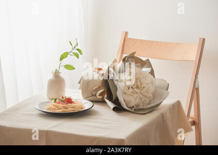 Handgemachte Pasta mit Ragout Soße auf Platte auf Vintage White Tisch mit Sieb und Blumen Stockfoto