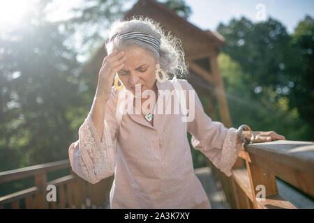 Frau tragende nette Ohrringe mit starken Kopfschmerzen Stockfoto