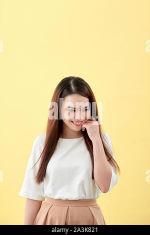 Schöne junge Frau mit langen schwarzen Haaren posiert auf gelbem Hintergrund Stockfoto
