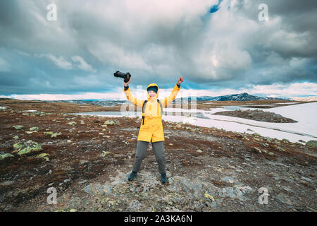 Aurlandsfjellet, Norwegen. Glückliche junge Frau touristische Reisende Fotograf mit der Kamera zu Fuß in der Nähe von Aurlandsfjellet Scenic Route Straße. Aktiven Lebensstil Stockfoto