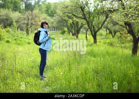 Ein Mädchen sammelt Schneeglöckchen im Wald. Schöne junge Frau taucht in den Strahlen der Frühlingssonne auf einer Lichtung im Wald. Stockfoto