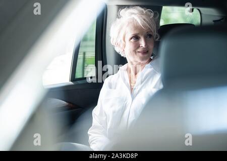 Weibliche Unternehmer office Reisen in ein luxuriöses Auto sitzt auf dem Rücksitz. Senior Geschäftsfrau im Auto. Stockfoto