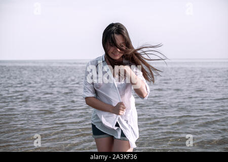 Lächelnde junge Frau genießen ihren Sommerurlaub am Strand. Schöne weibliche Model Spaß am Ufer Meeres. Stockfoto