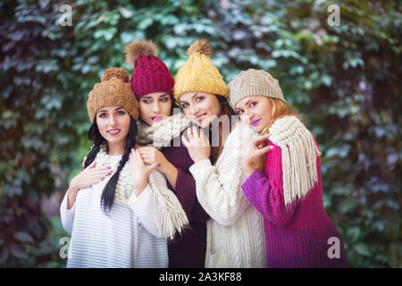 Vier Frauen, die besten Freunde kuscheln im Park in einem strickschal und Hüte. Stockfoto