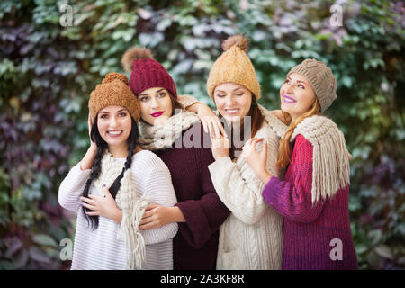 Vier Frauen, die besten Freunde kuscheln im Park in einem strickschal und Hüte. Stockfoto