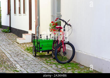 Ein Pushbike und Warenkorb außerhalb eines Hauses in einem gepflasterten allyway im Zentrum von Warmemunde, Rostock, Deutschland. Stockfoto