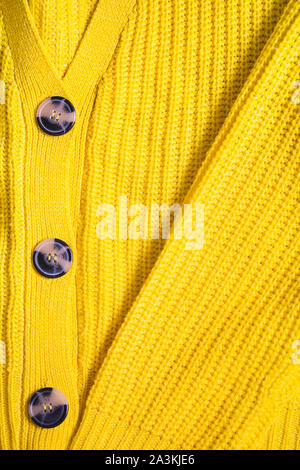 Gelb Orange Senf ocker Stricken wolle Textur Hintergrund. Winter oder Herbst Jacke oder Pullover mit Buttons close-up. Vertikale Ausrichtung, flach Stockfoto