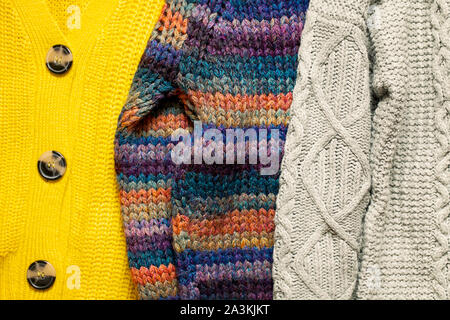 Bündel oder Stapel von stilvollen gemütlichen gestrickt Farbe Pullover mit verschiedenen Strickmuster. Textur der Wollene Sachen Hintergrund. Herbst Winter saison Strickwaren Stockfoto