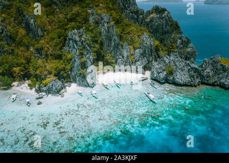 El Nido, Palawan, Philippinen. Luftaufnahme von tropischen Insel mit touristischen Boote am weißen Sandstrand. Alte Korallenriff vor jugged Karst Stockfoto