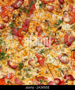 Gebackene Pizza mit geräuchertem Würstchen, Pilze, Tomaten, Käse und Dill, geschnitten Essen, Vollbild, Nahaufnahme Stockfoto