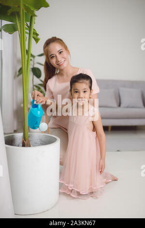 Mutter und Tochter Bewässerung von Pflanzen in der Wohnung Stockfoto