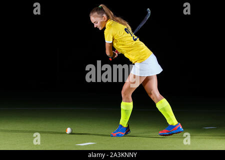 Hockey weibliche Spieler schlägt die Kugel mit Stock im Studio Stockfoto