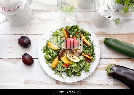 Salat von gegrilltem Gemüse auf Rucolasalat mit Pflaume, Pfirsich und Vinaigrette. Stockfoto