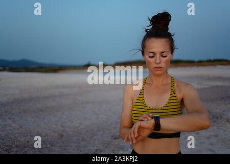 Fitness Sport Frau im Sport Style Kleidung am Strand am Abend mit Smart watch Gewicht in fitness App zu verfolgen. Stockfoto