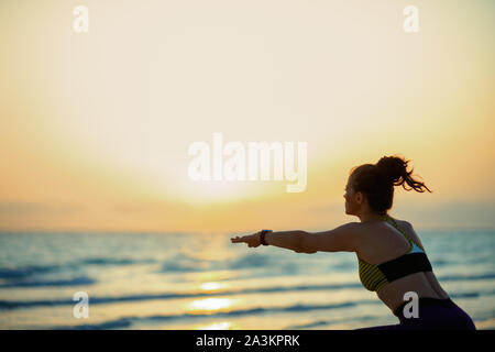 Silhouette von fit Sport Frau in Sport Kleidung am Strand abends hockt. Stockfoto