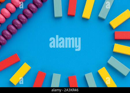 Rahmen aus Kinder Spielzeug, Ansicht von oben auf die pädagogische Spiele für Kinder auf blauem Papier Hintergrund. Buntes Holz- Ziegel, Abacus. Flach, kopieren Platz für Stockfoto