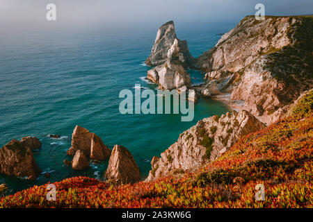Surreal und bizarr aufragenden Felsen am Strand Praia Da Ursa, Sintra, Portugal in Abend golden fire Abendlicht. Atlantikküste in der Nähe von Cabo da Stockfoto
