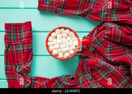 Heißer Kakao mit Marshmallow und rot karierten Hemd türkis Holztisch, Ansicht von oben. Weihnachten Hintergrund. Stockfoto